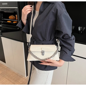 Detail of cream patent leather crossbody bag with silver twist lock and metal chain