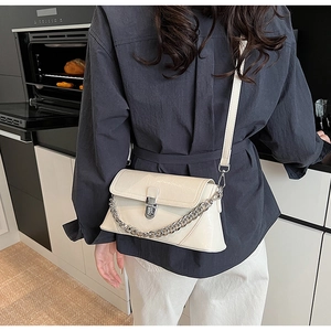 Detailed view of cream crossbody bag with crocodile texture and gold chain strap