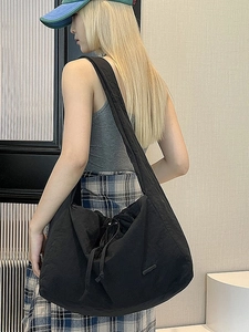 Black waterproof nylon tote bag with drawstring closure shown on shoulder for daily use