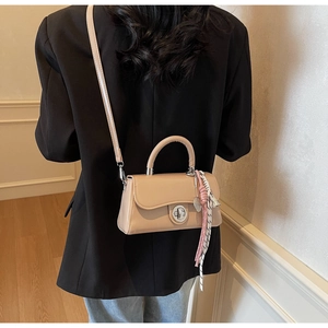 Detail van een beige crossbody tas met gevlochten touw en zilveren draaisluiting