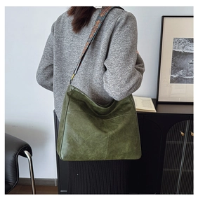 Detail of dark green hobo bag with embroidered wide strap and matte leather texture