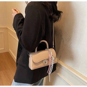 Detail van beige crossbodytas met metalen slot en gestreepte zijden sjaal accessoire