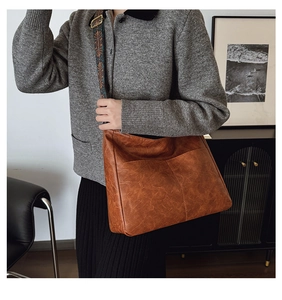 Vintage brown leather tote bag with colorful wide shoulder strap worn by a model