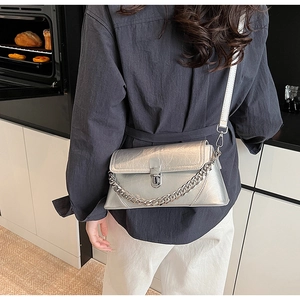 Detail of silver textured leather crossbody bag with chain and metallic buckle