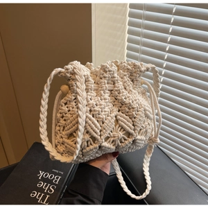 Detail of handmade macrame straw bucket bag with intricate weave and wooden bead drawstring