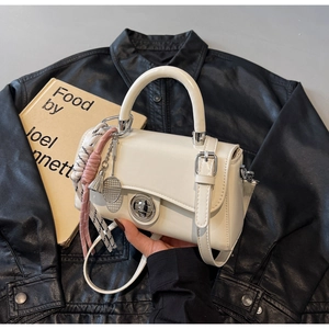 Detail van crème witte crossbody tas met zilveren sluiting en tennisracket hanger