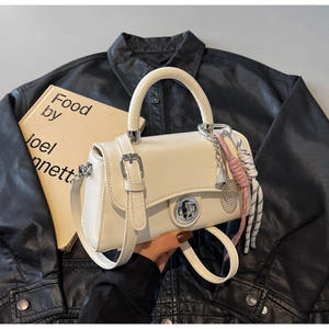 Close-up van witte crossbodytas met metalen slot en badminton hanger op lederen achtergrond