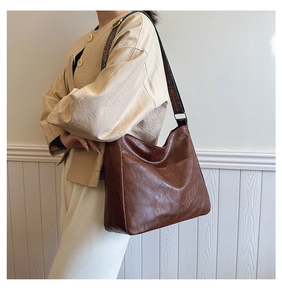 Macro detail of brown leather tote bag featuring a vintage ethnic pattern jacquard strap