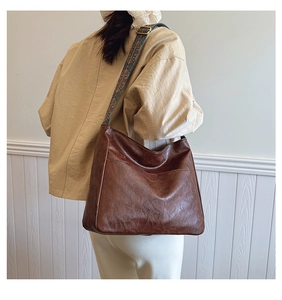 Detail of vintage brown tote bag with colorful bohemian wide jacquard strap on a model
