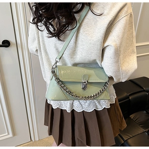 Close-up of light green patent leather shoulder bag with decorative metal chain detail