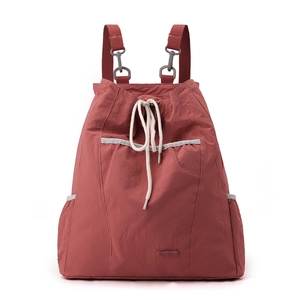Detalle de mochila de nylon terracota con cordón, tira reflectante y logotipo de la marca