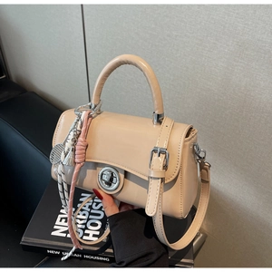 Detail van beige leren crossbodytas met zilveren draaisluiting en tennisracket bedel