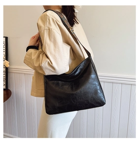 Close-up of black retro leather tote with a bohemian embroidered wide shoulder strap