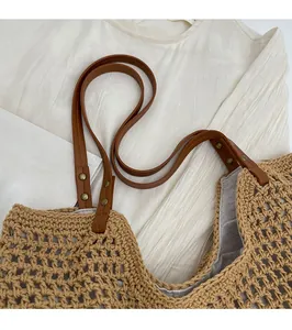 Detail of woven tote bag with brown faux leather straps and vintage bronze rivets