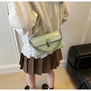 Detail of light green patent leather crossbody bag with silver chain and twist lock
