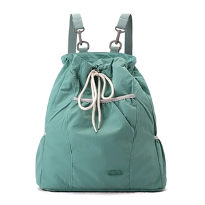 Detalle de una mochila de nailon verde Morandi con cordón ajustable y bolsillo lateral con cremallera