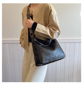 Detail of black leather hobo bag featuring vintage ethnic embroidery wide shoulder strap