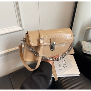 Detail of khaki glossy handbag with silver metal buckle and textured patent leather
