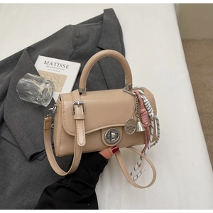 Detail van beige lederen crossbodytas met tennisracket en badmintonhangers aan de tas