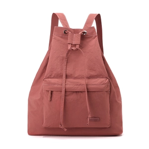 Detail of brick red drawstring backpack with contrast white stitching and silver eyelets