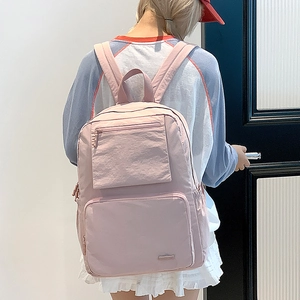 Détail du sac à dos en nylon rose clair avec doubles poches zippées et poches latérales