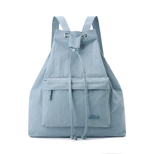Close-up of light blue nylon backpack featuring a drawcord closure and front zipper pocket