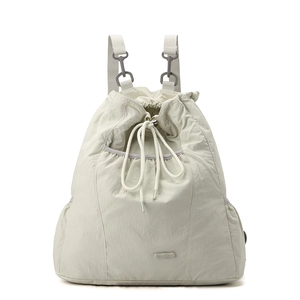 Detalle de una mochila de nailon beige claro con bolsillos de cordón y correas tejidas