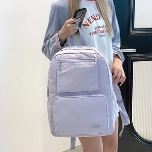Détail du sac à dos en nylon lilas avec deux poches frontales zippées et poignée supérieure
