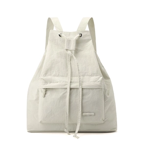 Detail view of the drawstring closure and front zip pocket of the ivory nylon backpack