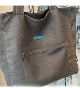 Close-up of a grey canvas tote bag with a blue bow print and a functional front pocket