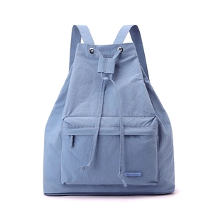 Close-up of light blue drawstring backpack showing nylon texture and logo detail