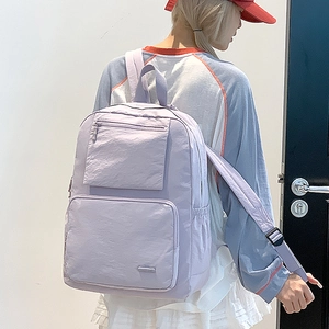 Détail du sac à dos en nylon violet clair montrant les poches latérales et la fermeture
