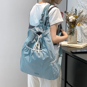 Detalle de la mochila de nailon azul claro con cordón y amplia capacidad interior