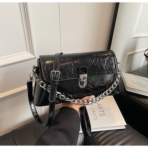 Detail of black crinkled leather shoulder bag featuring a silver chain and metal clasp