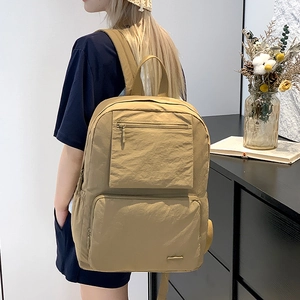 Détail du sac à dos en nylon kaki avec plusieurs poches zippées et compartiment latéral gourde