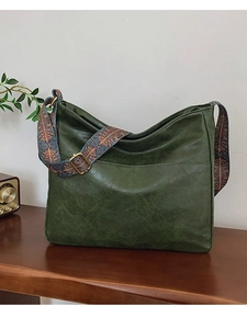 Dark green vintage tote bag with wide ethnic pattern strap on wooden background