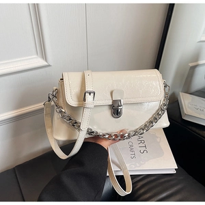 Detail of cream-white glossy patent leather handbag with silver chain and metal clasp