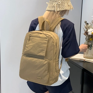 Détail du sac à dos en nylon marron clair avec plusieurs poches et texture imperméable