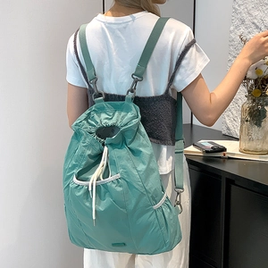 Detalle de mochila de nailon verde azulado con cordón y ganchos metálicos