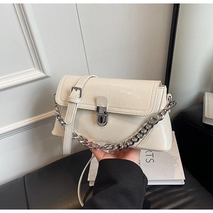 Detail of cream-white glossy handbag with silver rotary lock and chunky metal chain