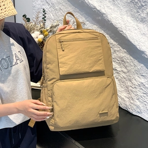 Détail du sac à dos en nylon kaki avec poche latérale et compartiments zippés sur modèle