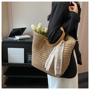 Detail of hand-woven straw tote with leather strap and delicate lace ribbon decoration