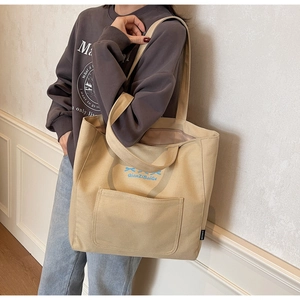 Close-up of canvas tote bag featuring double handles and a blue bow graphic design
