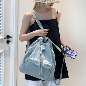 Detail showing light blue nylon backpack with drawstring closure and front zipper pocket