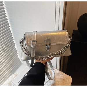 Detail of silver metallic textured crossbody bag featuring chain strap and lock closure