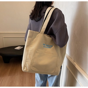 Detail of canvas tote bag with blue bow embroidery and wide shoulder strap comfort