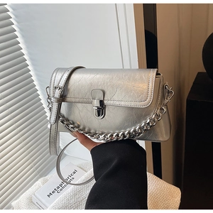 Detail of silver wrinkled leather texture with metal chain and lock on shoulder bag