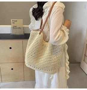 Close-up of minimalist beige woven tote bag with brown leather strap worn by a model