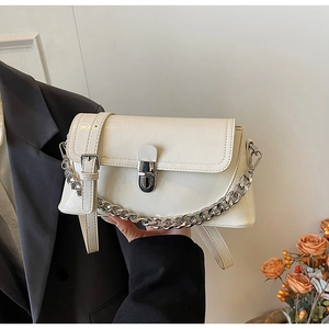 Detail of beige faux leather handbag with silver lock, thick chain and adjustable strap
