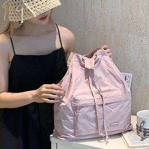 Detail of light purple drawstring backpack made of soft nylon texture shown with accessories